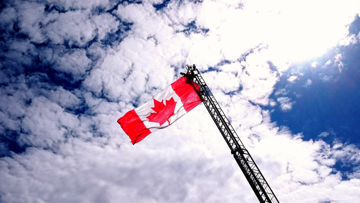 the canadian flag on a crane against a blue sky